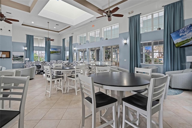 tiled dining area with beam ceiling, ceiling fan, a high ceiling, coffered ceiling, and crown molding