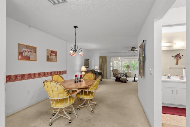 carpeted dining room with sink, a textured ceiling, and ceiling fan with notable chandelier