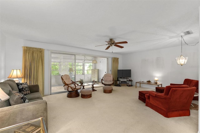 carpeted living room with ceiling fan with notable chandelier