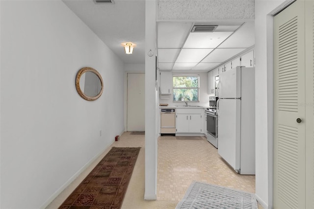 kitchen with white cabinetry, white appliances, and sink