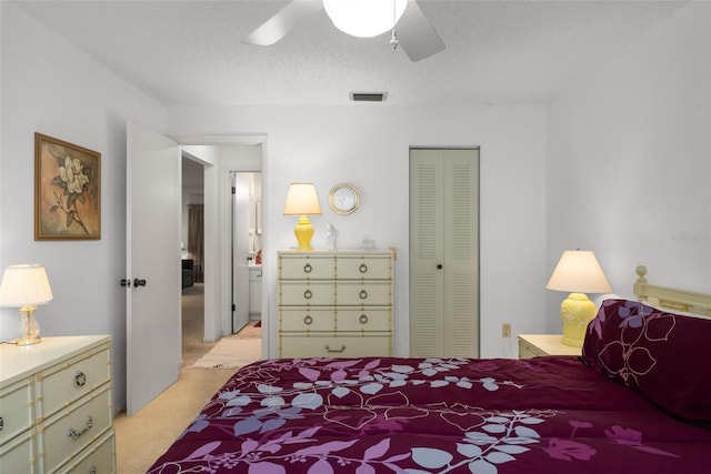 bedroom with a closet, a textured ceiling, light colored carpet, and ceiling fan