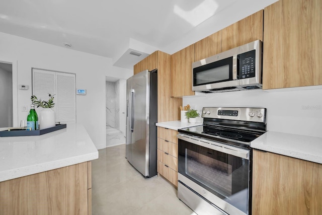 kitchen with light stone countertops, light tile patterned floors, and stainless steel appliances