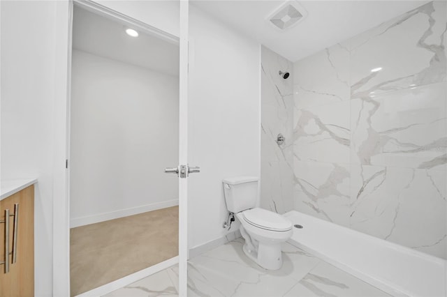 bathroom featuring a tile shower, vanity, and toilet