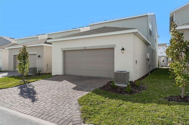 view of home's exterior with a garage, a yard, and central air condition unit