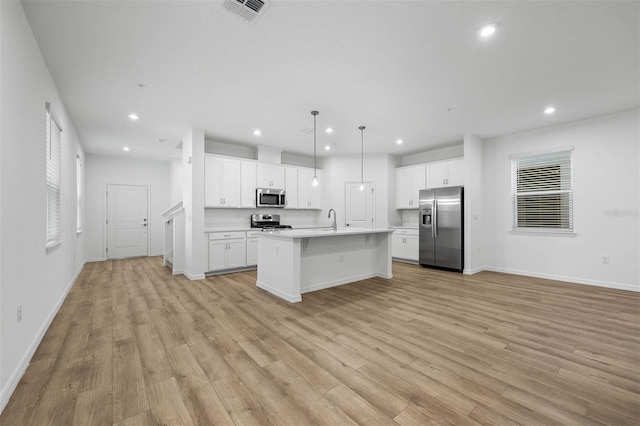 kitchen featuring white cabinetry, appliances with stainless steel finishes, a kitchen island with sink, and decorative light fixtures