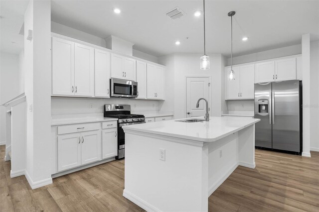 kitchen with white cabinetry, sink, stainless steel appliances, and a center island with sink