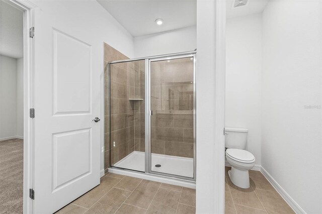 bathroom with tile patterned floors, toilet, and an enclosed shower