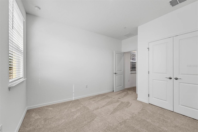 unfurnished bedroom with light carpet and a closet