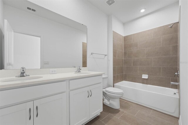 full bathroom featuring tiled shower / bath, vanity, tile patterned floors, and toilet