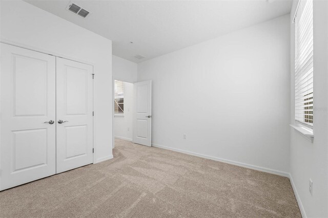 unfurnished bedroom with light carpet and a closet