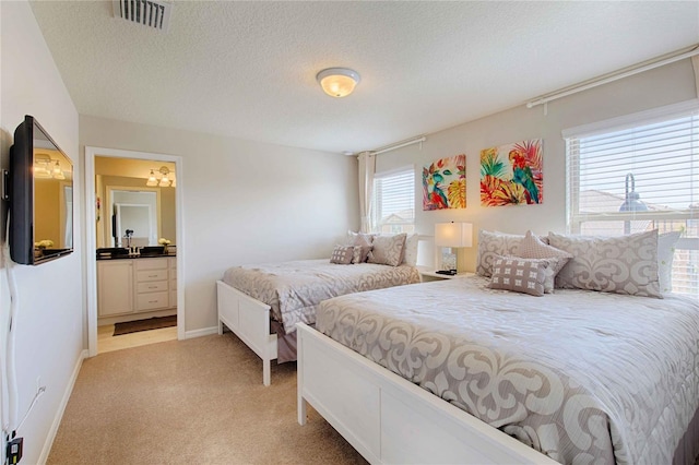 bedroom with multiple windows, a textured ceiling, and light colored carpet