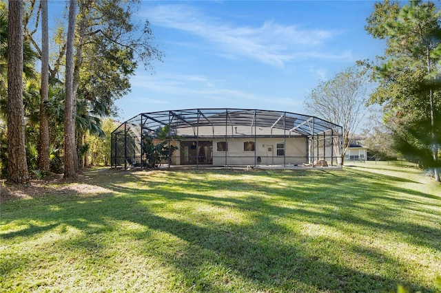 rear view of house with glass enclosure and a yard