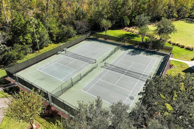 view of tennis court featuring fence and a lawn