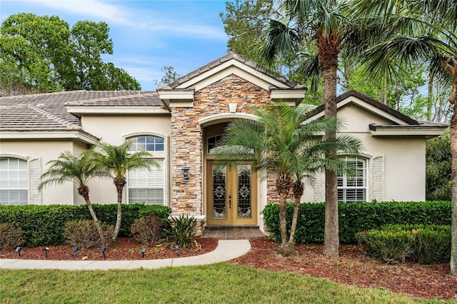 entrance to property with stone siding, stucco siding, and french doors