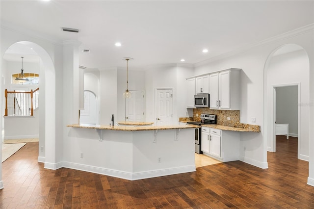 kitchen featuring visible vents, decorative backsplash, light stone counters, a breakfast bar, and stainless steel appliances