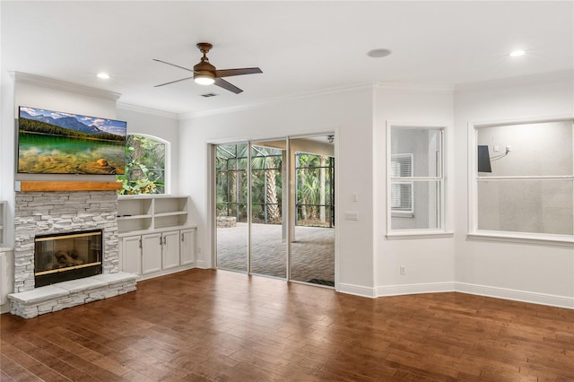 unfurnished living room with baseboards, visible vents, wood finished floors, crown molding, and a stone fireplace