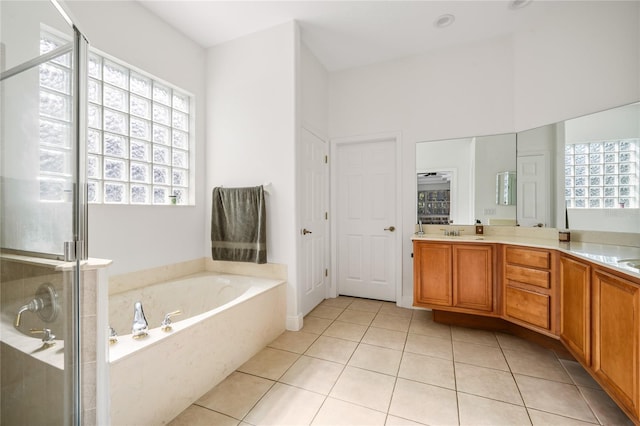 bathroom featuring tile patterned flooring, a sink, a shower stall, a bath, and double vanity