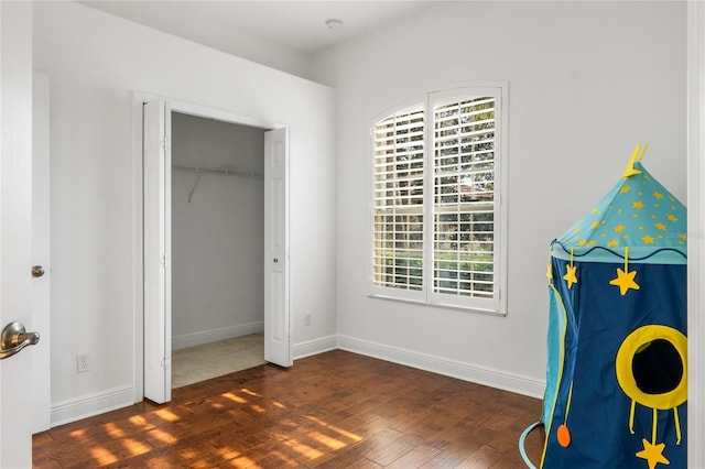 unfurnished bedroom with a closet, baseboards, and wood finished floors