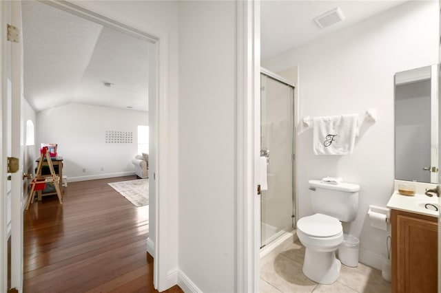 bathroom featuring visible vents, toilet, vaulted ceiling, a shower stall, and wood finished floors