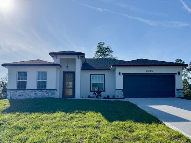 prairie-style home with stone siding, concrete driveway, an attached garage, and a front yard