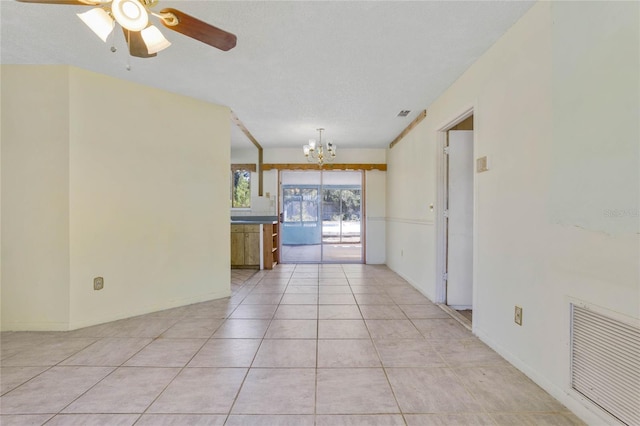 unfurnished room with ceiling fan with notable chandelier, light tile patterned flooring, and a textured ceiling