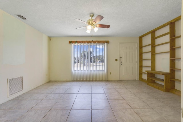 tiled spare room featuring ceiling fan and a textured ceiling