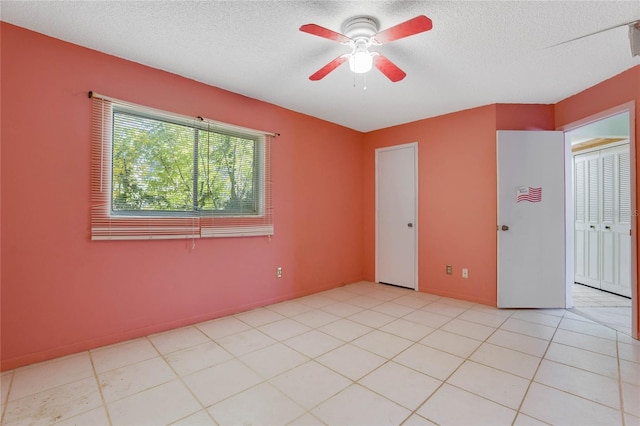 tiled spare room featuring a textured ceiling and ceiling fan