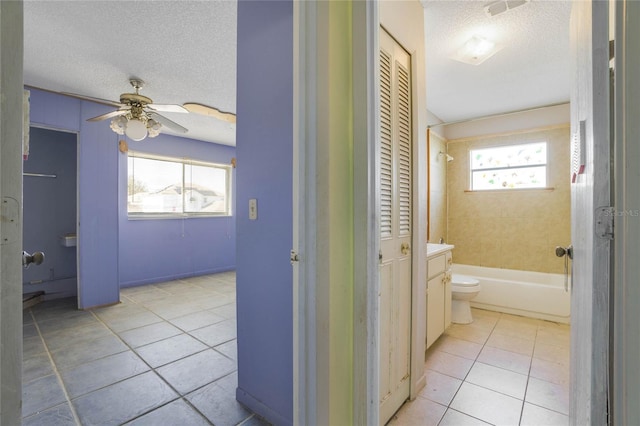 bathroom with tile patterned flooring, a textured ceiling, toilet, and tiled shower / bath