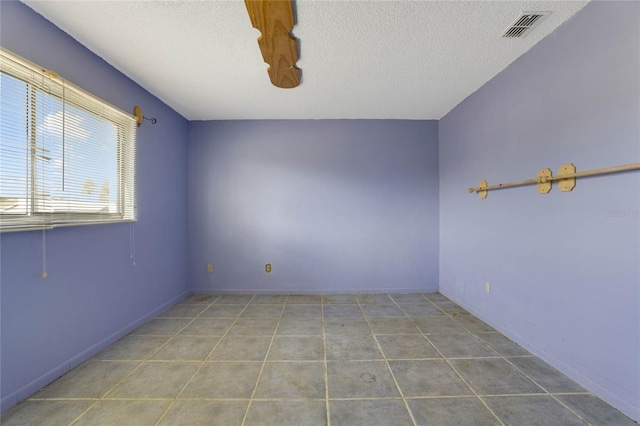 tiled spare room with a textured ceiling