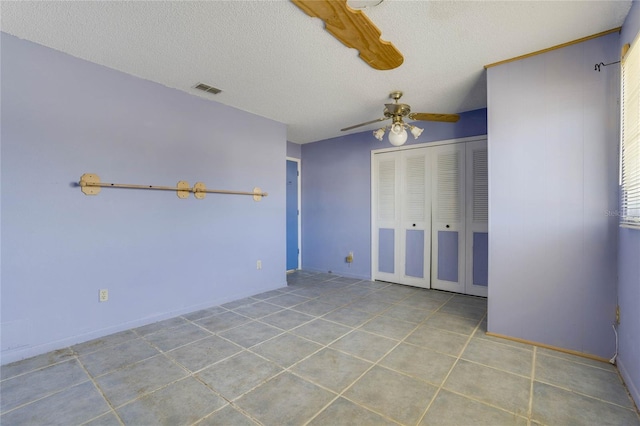 unfurnished bedroom with light tile patterned floors, a textured ceiling, a closet, and ceiling fan