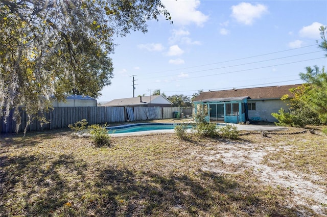 view of yard featuring a fenced in pool and a sunroom