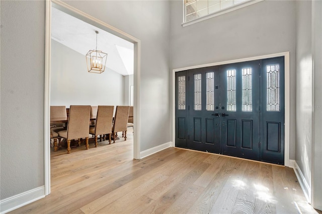 entryway with wood-type flooring, a high ceiling, and a notable chandelier