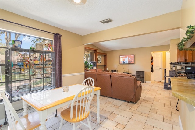 tiled dining room with a textured ceiling and vaulted ceiling