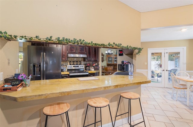 kitchen featuring kitchen peninsula, electric range, black refrigerator with ice dispenser, and a breakfast bar