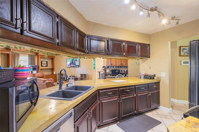 kitchen with kitchen peninsula, light tile patterned floors, sink, and stainless steel appliances