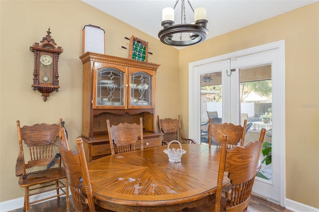 dining space with dark hardwood / wood-style flooring, a textured ceiling, and an inviting chandelier