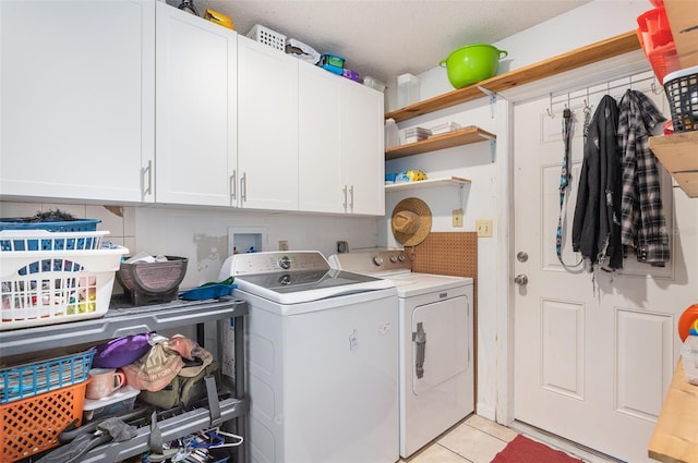 laundry area featuring light tile patterned floors, cabinets, a textured ceiling, and independent washer and dryer