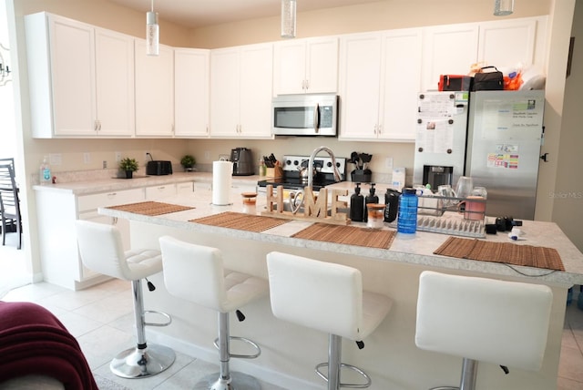 kitchen featuring white cabinetry, a kitchen bar, appliances with stainless steel finishes, and light tile patterned flooring