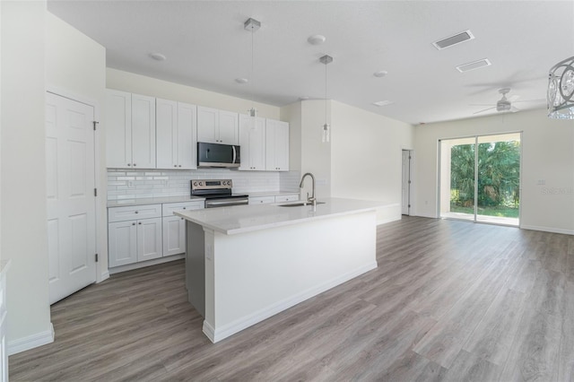 kitchen featuring light wood finished floors, a sink, light countertops, stainless steel appliances, and backsplash