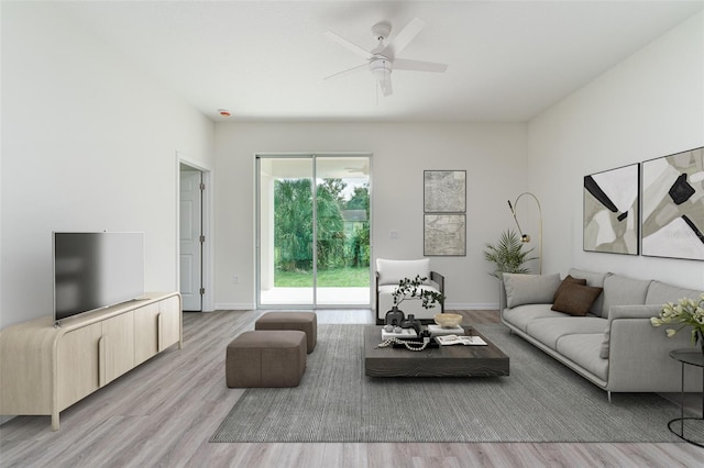 living area with light wood-style floors, baseboards, and a ceiling fan