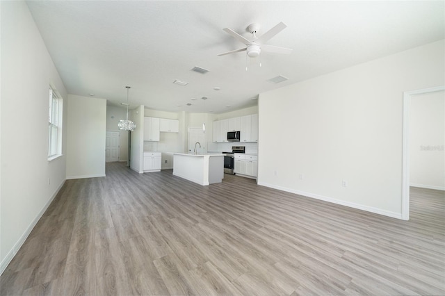 unfurnished living room with a ceiling fan, light wood-type flooring, visible vents, and baseboards