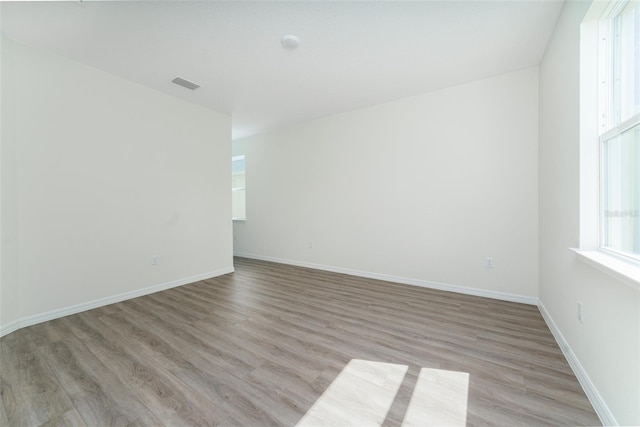 unfurnished room with light wood-type flooring, visible vents, and baseboards