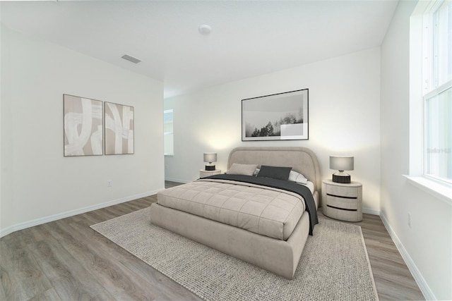 bedroom featuring baseboards, visible vents, and wood finished floors