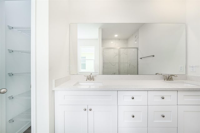 bathroom featuring a spacious closet, a marble finish shower, and a sink