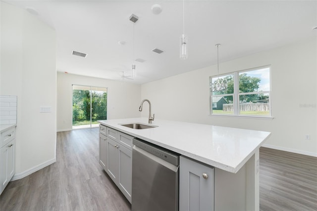 kitchen featuring light wood-style flooring, a sink, visible vents, dishwasher, and decorative light fixtures