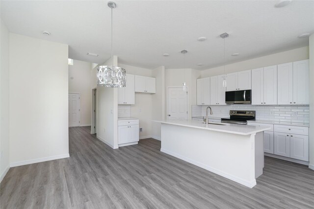 kitchen featuring light wood-style flooring, stainless steel appliances, a sink, white cabinets, and decorative backsplash