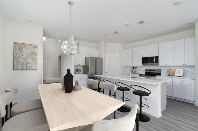 kitchen featuring a center island with sink, decorative backsplash, appliances with stainless steel finishes, a kitchen bar, and a sink