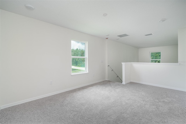 empty room with carpet floors, visible vents, and baseboards