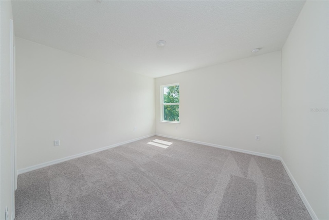 carpeted spare room with baseboards and a textured ceiling