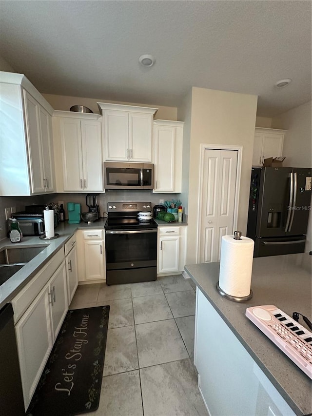 kitchen featuring white cabinets, appliances with stainless steel finishes, sink, and light tile patterned floors